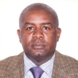 Callist Tindimugaya in a suit and tie is posing for a photo.