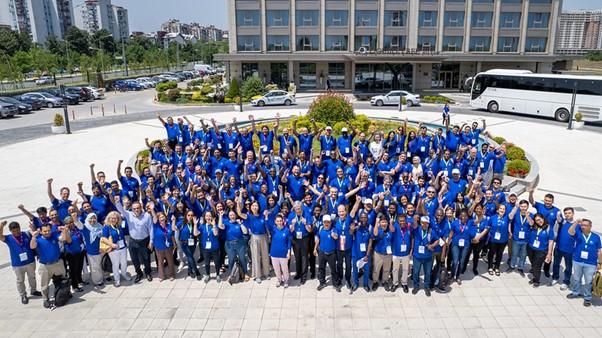 A group of people in blue shirts standing in front of a building.