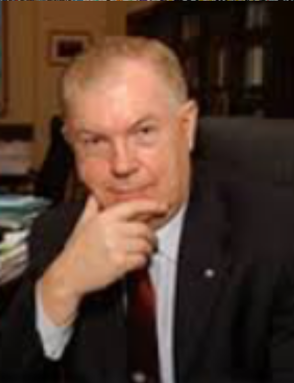 A man in a suit sits at a desk.