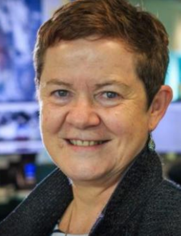 A woman smiling in front of a computer screen.