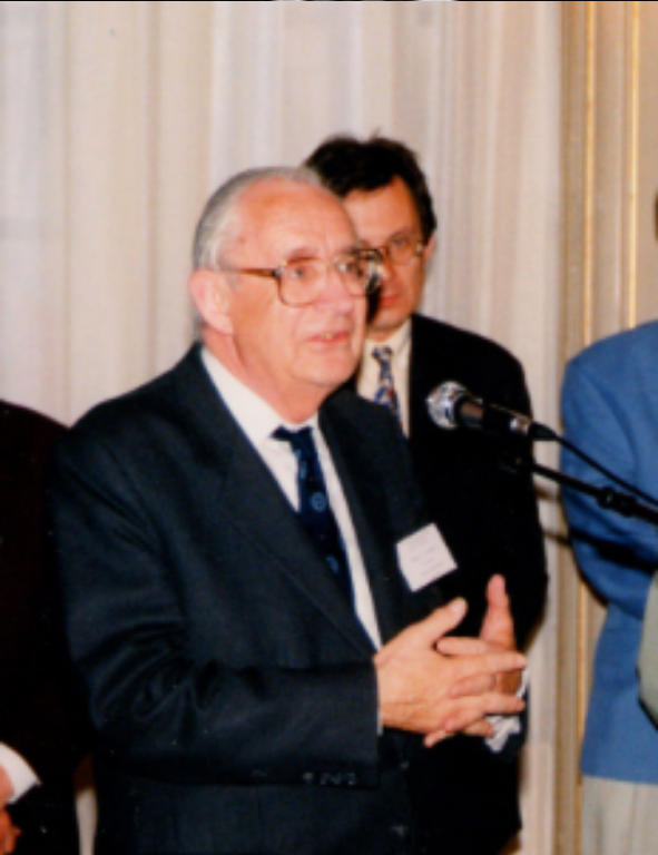 A man in a suit standing in front of a microphone.