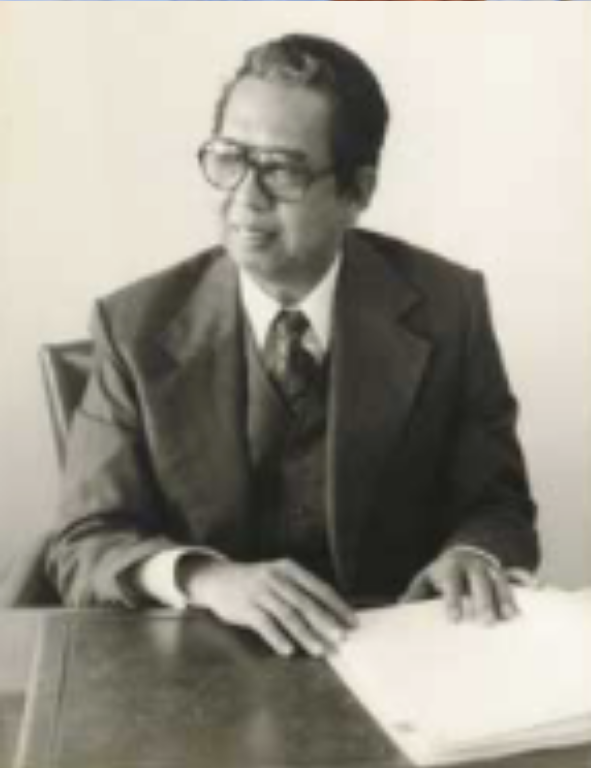 A black and white photo of a man sitting at a desk.