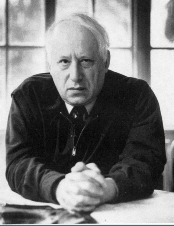 A black and white photo of a man sitting at a table.