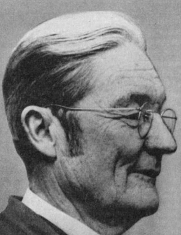 A black and white photo of a man wearing glasses.