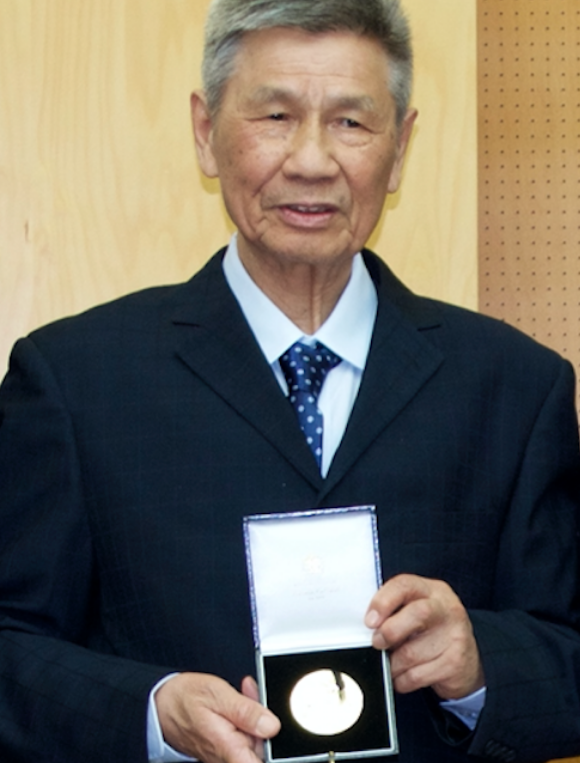 Two men in suits standing next to each other holding a medal.