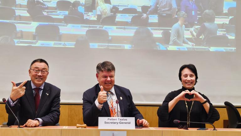 Three people sitting at a table and giving the thumbs up.