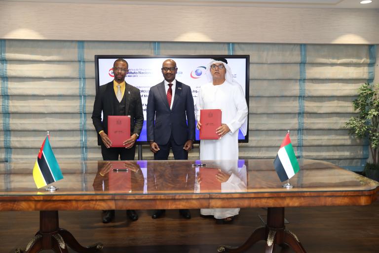 Three men standing in front of a table with flags.