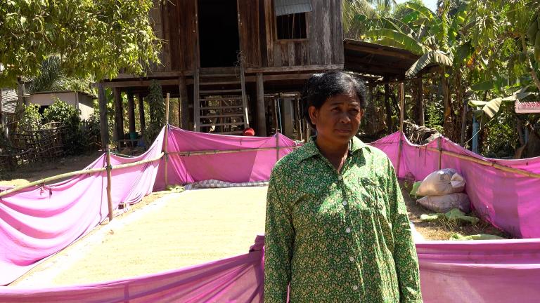 A woman standing in front of a purple tarp in front of a house.