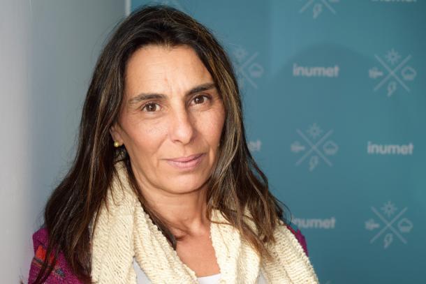 A woman wearing a scarf and standing in front of a wall.