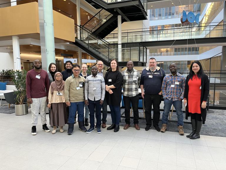 Group of professionals posing together in a bright and modern office atrium.