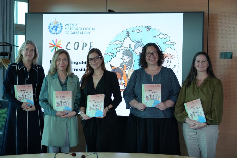 Five women stand in front of a presentation screen holding books titled "Climate Change," with the World Meteorological Organization and COPE logos displayed on the screen behind them.