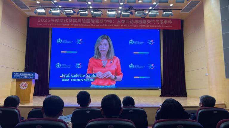 Audience watches a lecture by Prof. Celeste Saulo, WMO Secretary-General, presented on a large screen at a climate science event in an auditorium.