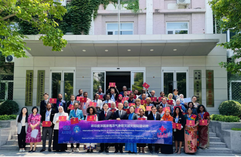 A large group of people pose outside a building holding certificates, standing behind a banner for an international training course on schistosomiasis and malaria prevention.