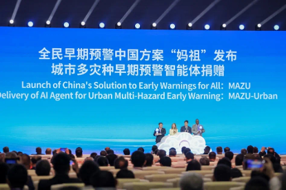 A panel of speakers stands on stage at a conference, with a large screen behind displaying information about China's early warning solutions for multi-hazard urban events.