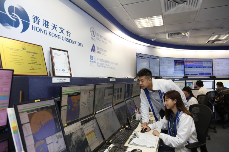 Meteorologists at the Hong Kong Observatory monitor weather data and forecasts on multiple computer screens in a control room.