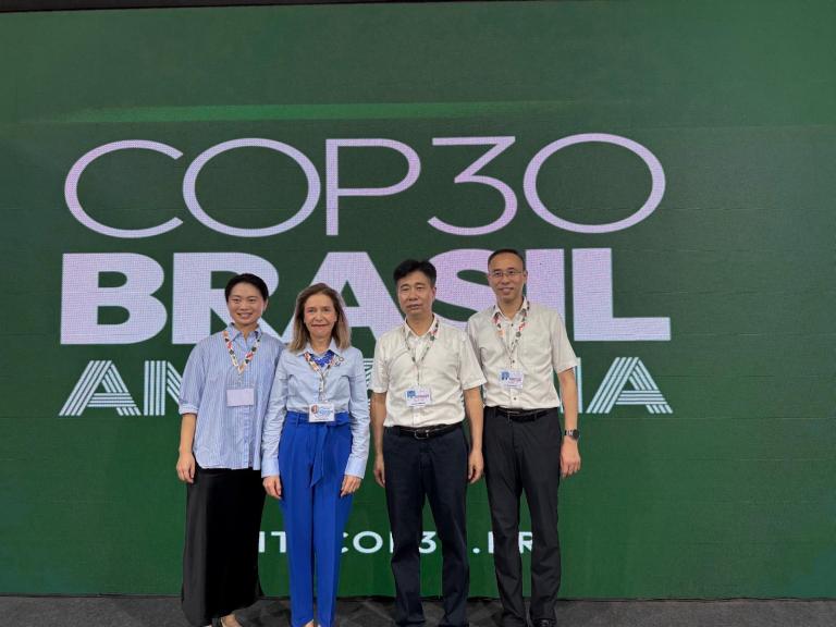 Four people stand in front of a large green backdrop displaying the words "COP30 Brasil Amazônia.