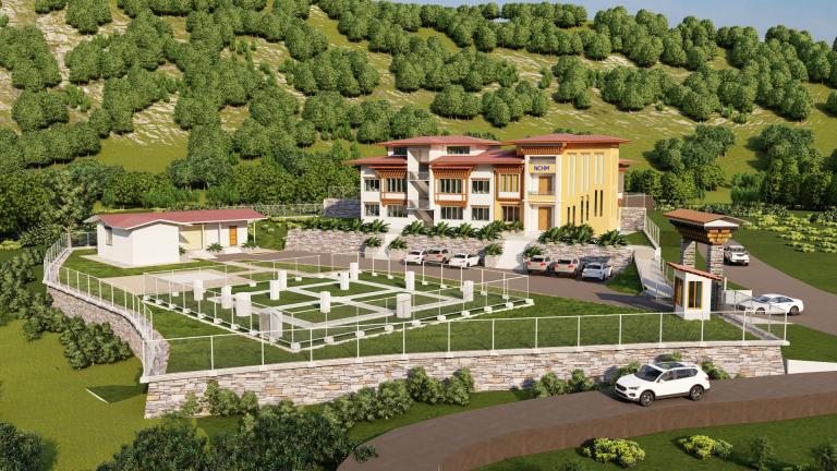 A gated property with a modern multi-story building, parking area, several cars, an entrance booth, and landscaped grounds surrounded by trees and hills.