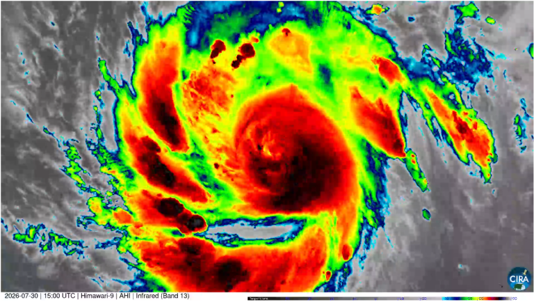 Infrared satellite image of a hurricane shows intense red, yellow, and green cloud bands spiraling around a defined eye.