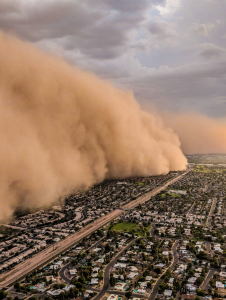 A huge cloud of sand blows over a city.