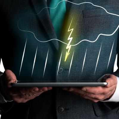 A person in a suit holds a tablet displaying a digital illustration of a cloud with rain and lightning.