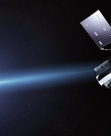 A satellite with solar panels orbits Earth in space, with the planet’s blue surface and a bright light visible on the left side.