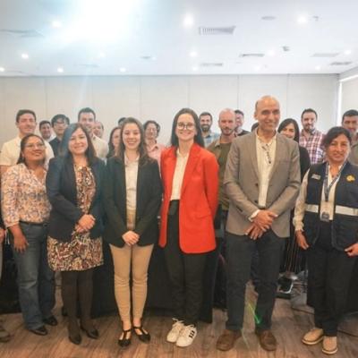 A group of people pose for a photo in a conference room, standing in front of a Senamhi banner and a projection screen.