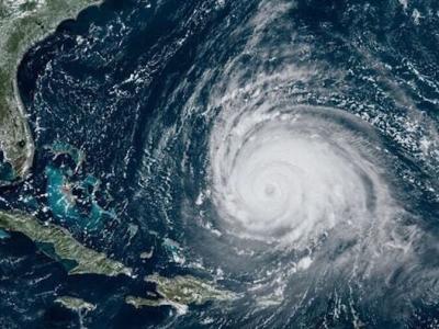 Satellite image showing a large hurricane with a well-defined eye over the Atlantic Ocean, approaching the southeastern coast of the United States and the Caribbean.